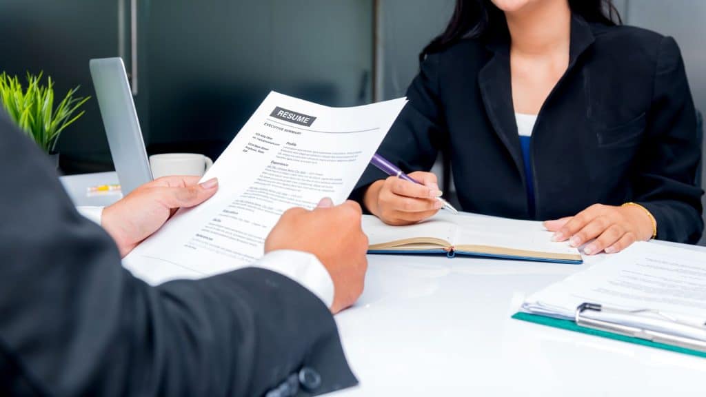 Un homme qui tien un CV avec une femme en face qui prend des notes